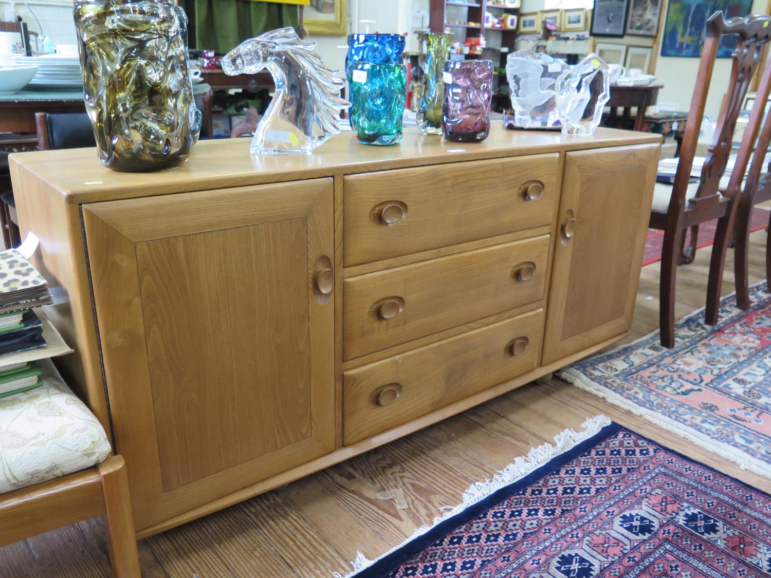 An Ercol elm Windsor sideboard, with three central drawers (the top drawer with cutlery insert)