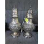 A pair of silver peppers decorated in high relief