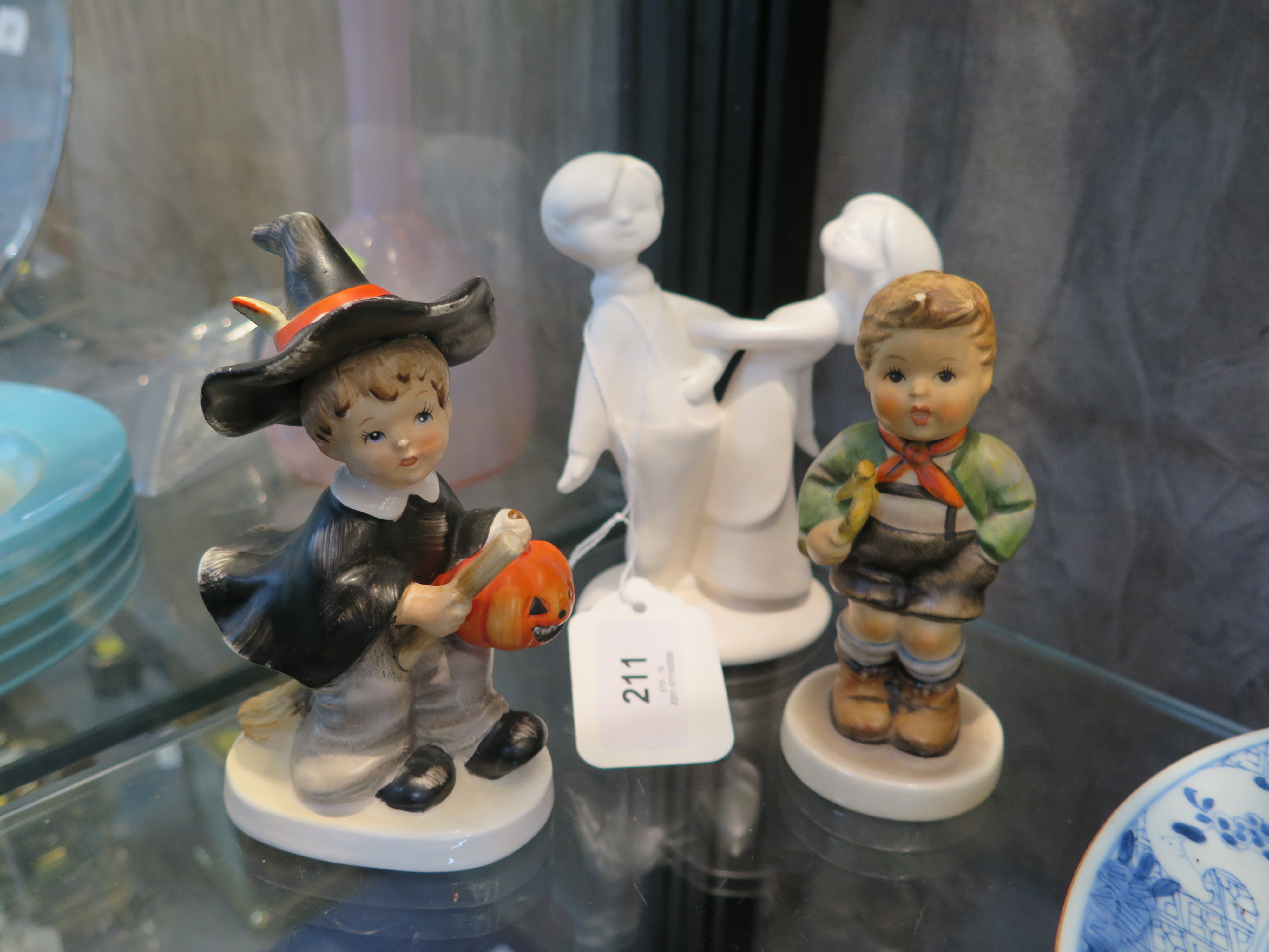 A Halloween figure of a child in witches costume, seated in on a broom holding a pumpkin, together
