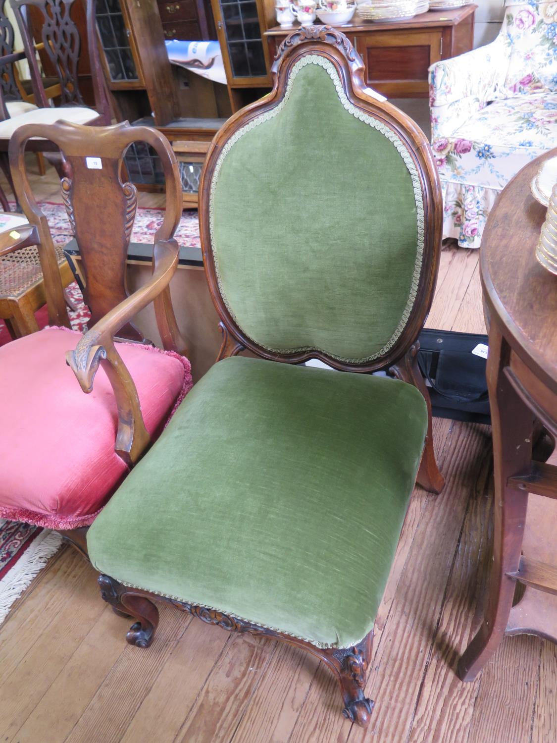 A Victorian walnut framed low nursing chair with heart shaped back upholstered in green dralon plush