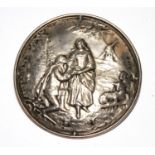 A silver brooch depicting two lovers