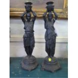 A pair of black painted metal candelabra, in the form of Classical figures holding up urns, 40 cm