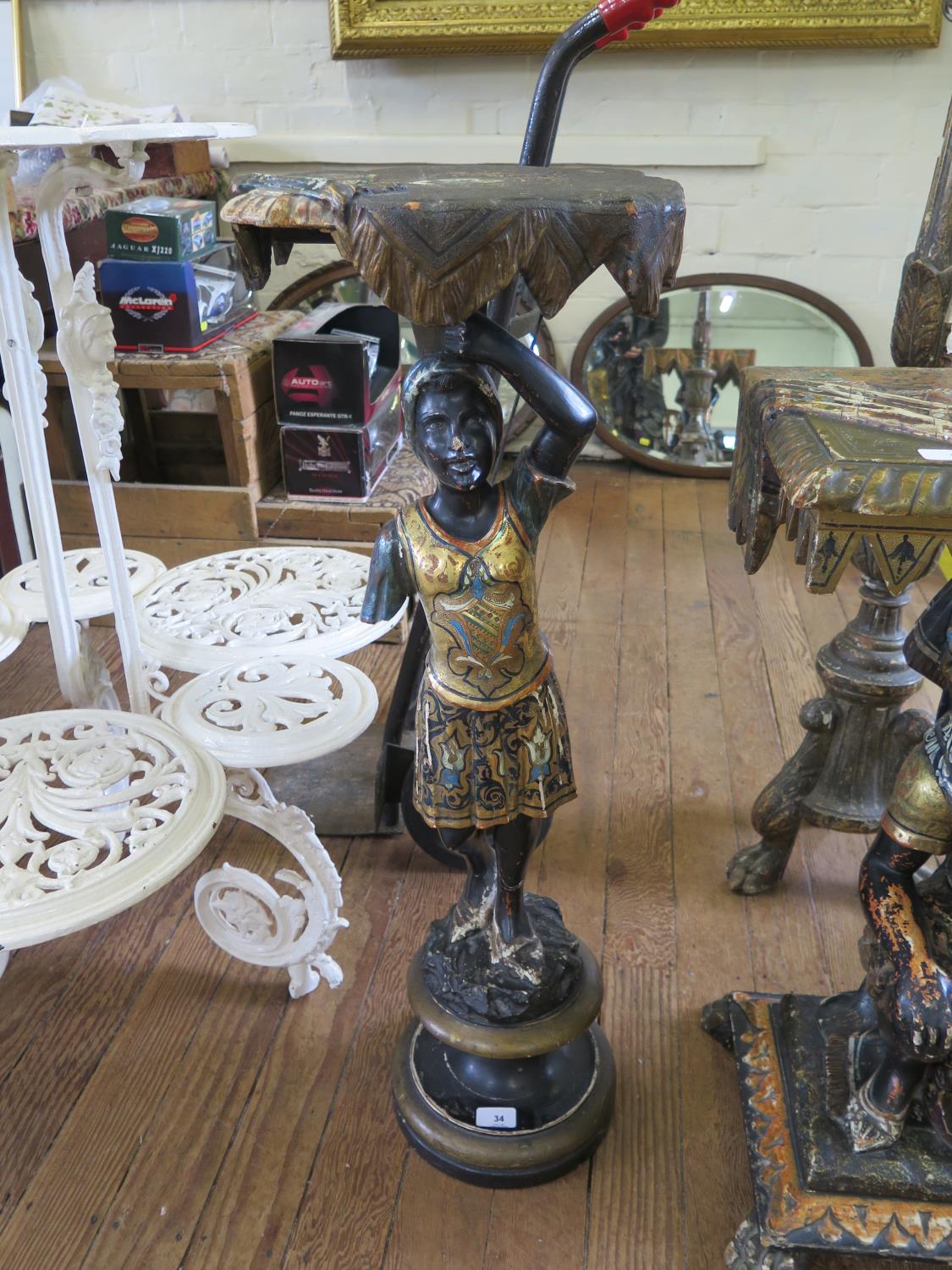 A 19th century Italian Blackamoor torchere stand, the shaped rectangular top carved and styled as