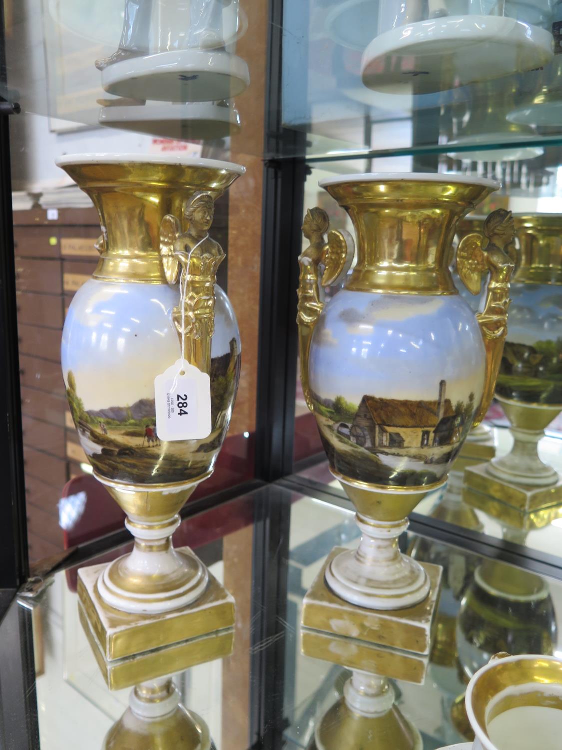 A pair of early 19th century gilt decorative vases, with angel twin handles, hand painted with river