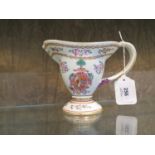 A Chinese export style jug, with entwined handle, enamelled floral sprays and coat of arms, 13 cm