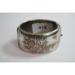 A silver colour metal bangle decorated in gold washed flowers and leaves