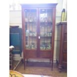 An Edwardian boxwood lined mahogany display cabinet, with glazed and panelled doors on turned