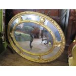 An oval giltwood wall mirror, with panelled border, 92 cm x 72 cm, and a shaped giltwood mirror