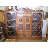 An Edwardian walnut bookcase cabinet, the raised back over a drawer and a pair of rosette and urn