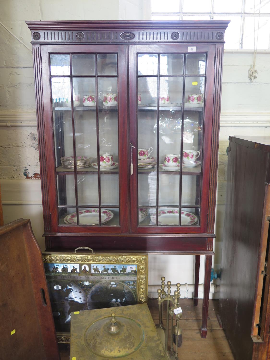 An Edwardian mahogany display cabinet, the fluted and rosette frieze over a pair of glazed doors