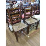 A pair of turned ash ladderback chairs, with rush seats on turned legs with pad feet and