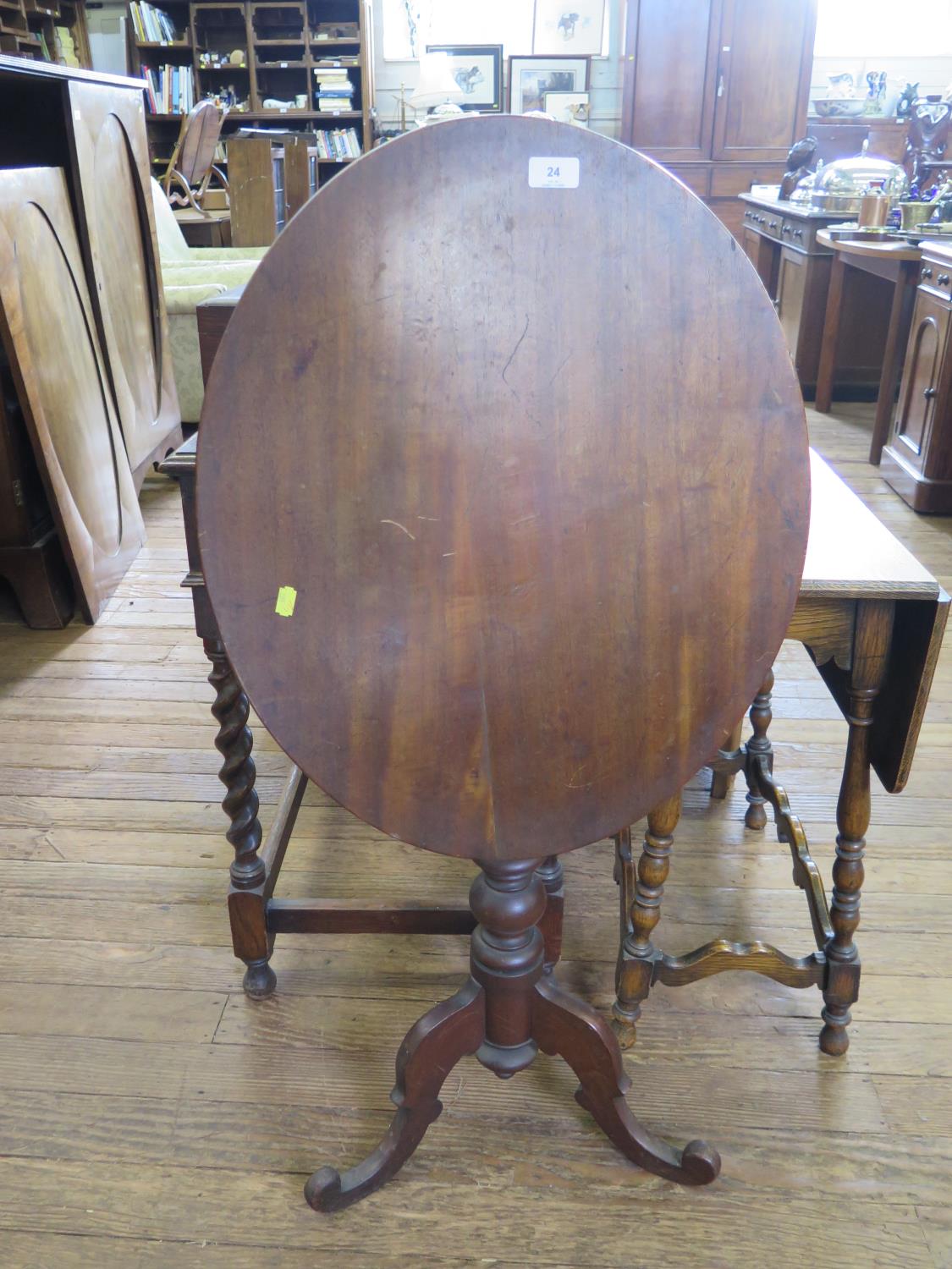 A 19th century mahogany snap-top tripod table, the oval top on a baluster stem and scrolled legs,