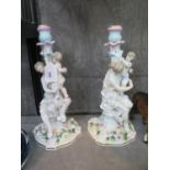 A pair of continental porcelain candlesticks, depicting a mother and child on rose encrusted