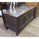 An 18th century oak coffer, the panelled hinged lid over a lozenge and scroll carved front, 125 cm