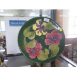 A Moorcroft Pottery Hibiscus pattern plate, with a green ground, paper label to the base, 30.5 cm