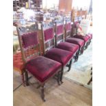 A set of six late Victorian oak dining chairs, the carved shaped top rails over padded and rail