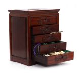 A SMALL WOODEN TABLE TOP CHEST OF FIVE DRAWERS containing various silver and jewellery, the chest