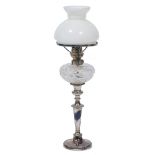 A TABLE LAMP constructed from a silver plated candlestick and cut glass reservoir and white glass