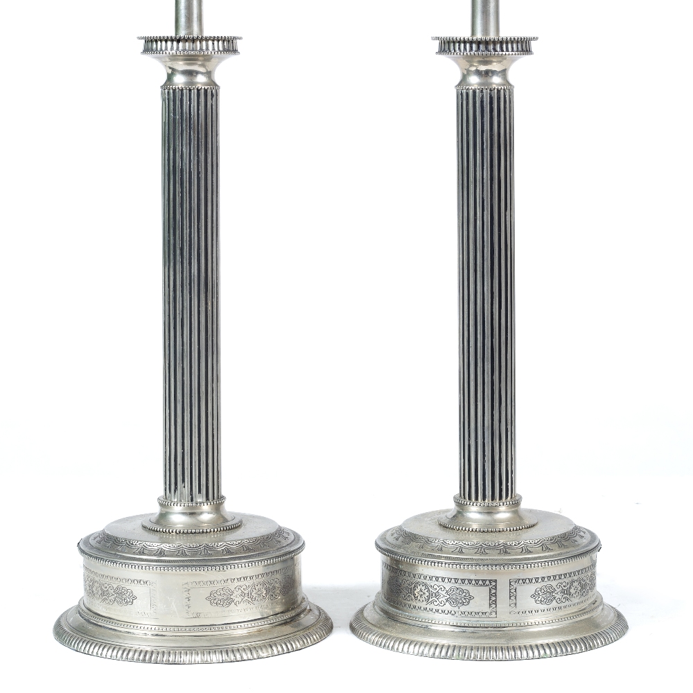 A PAIR OF SILVERED METAL TABLE LAMPS with reeded column and circular base with engraved