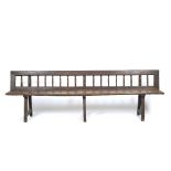 AN ANTIQUE OAK HIGH BACKED BENCH OR SETTLE with turned spindles to the back, planked seat and