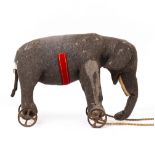 AN EARLY 19TH CENTURY STEIFF GREY FELT ELEPHANT on iron wheels and with button to the ear, 41cm long