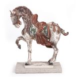 A TANG STYLE PAINTED POTTERY HORSE set on a composite stone base, 46cm wide x 49cm high overall