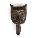 AN ANTIQUE BRASS OR POSSIBLY BRONZE DOOR KNOCKER in the form of a cat mask with glass eyes,