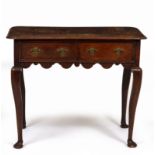 A GEORGE III OAK SIDE TABLE with rounded corners, two drawers and standing on turned tapering legs