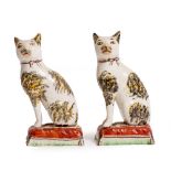 A PAIR OF 19TH CENTURY STAFFORDSHIRE POTTERY CATS each 10cm wide x 18cm high At present, there is no