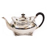 AN EDWARDIAN SILVER TEAPOT with gadrooned rim and ebonised handle, and standing on scroll