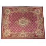 AN 18TH CENTURY FRENCH STYLE NEEDLEWORK BURGUNDY GROUND SMALL CARPET with central cartouche within a