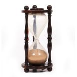AN ANTIQUE ROSEWOOD HOUR GLASS with turned supports, 8cm diameter x 16.5cm high Condition: the