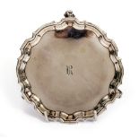 A SMALL GEORGE II SILVER SALVER OR STAND with piecrust edge and scroll feet, later engraved with