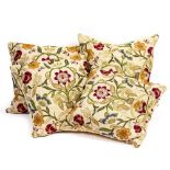 A SET OF FOUR CUSHIONS with embroidered flower decoration on a cream ground, backed in gold silk and