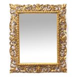 A VENETIAN STYLE FOLIATE CARVED GILTWOOD FRAMED MIRROR with bevelled mirror plate, 58cm wide x