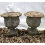 A PAIR OF RECONSTITUTED STONE GARDEN URNS with acanthus leaf moulded bodies and square bases, 51cm