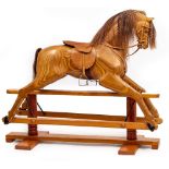 A RELKO LAMINATED WOODEN ROCKING HORSE with a leather saddle, 150cm wide x 120cm high At present,