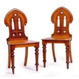 A PAIR OF 19TH CENTURY OAK GOTHIC STYLE HALL CHAIRS with pierced backs, solid seats and turned