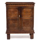 AN ANTIQUE CARVED OAK AND PANELLED CUPBOARD with twin doors opening to reveal shelves and raised