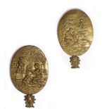 A PAIR OF CONTINENTAL BRASS OVAL PLAQUES depicting relief pictures of people worshiping at Cupid's