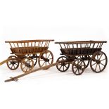 TWO SIMILAR OLD WOODEN HAND CARTS with iron bound splaying tops and pivoted front axles with