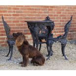 A BLACK PAINTED CAST IRON CIRCULAR TABLE with wooden top, the legs cast with terms in the form of