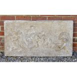 A CAST RECONSTITUTED STONE PLAQUE depicting classical figures cavorting in the sea, 96.5cm wide x