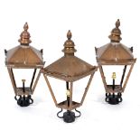 A SET OF THREE COPPER TAPERING FOUR GLASS LANTERNS with wrought iron brackets, the lanterns 26cm
