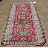 A MODERN KAZAK RED GROUND RUNNER with geometric motifs to the central field and within a triple