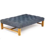 A LARGE OAK NAVY AND BUTTON UPHOLSTERED STOOL with square legs united by a H stretchers, 130cm x