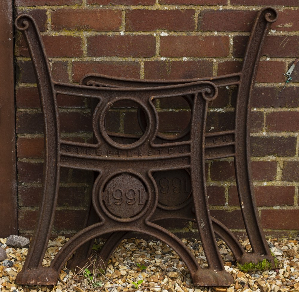 A PAIR OF 'STREET MASTER' CAST IRON BENCH ENDS each with a roundel bearing the date 1991 and each