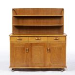 AN ERCOL STYLE ELM SIDE CABINET with low plate rack above three drawers and over a single cupboard