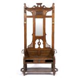 AN EARLY 20TH CENTURY OAK HALL STAND the mirrored back with carved decoration and hooks, the seat