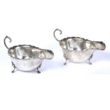 A PAIR OF SILVER SAUCE BOATS with scrolling handles, shaped edges and hoof feet by Wilson & Sharp